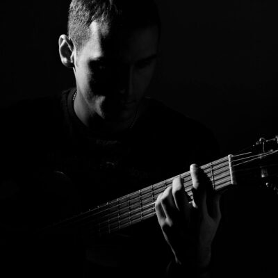 Grayscale Photo of Man Playing Guitar
